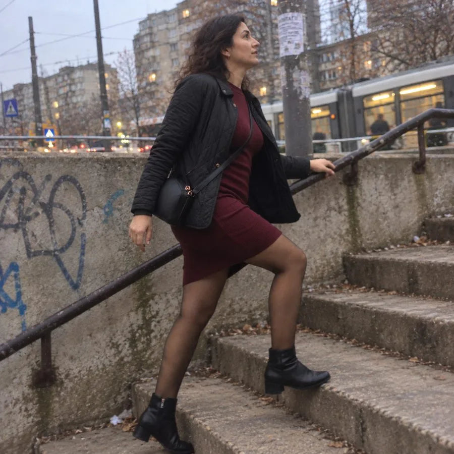 Lépcsőn felfelé sétáló nő ruhában és leggingsben